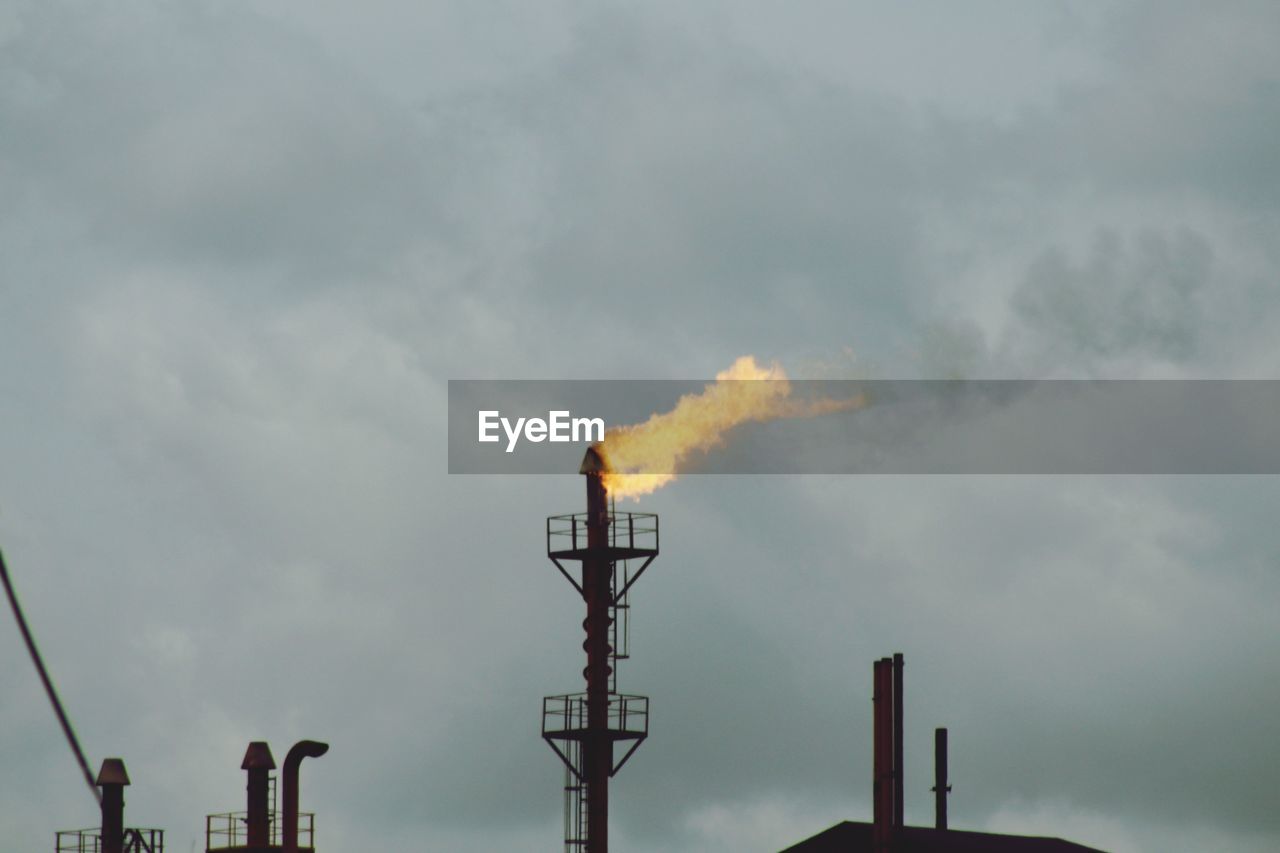 Low angle view of smoke emitting from chimney against sky