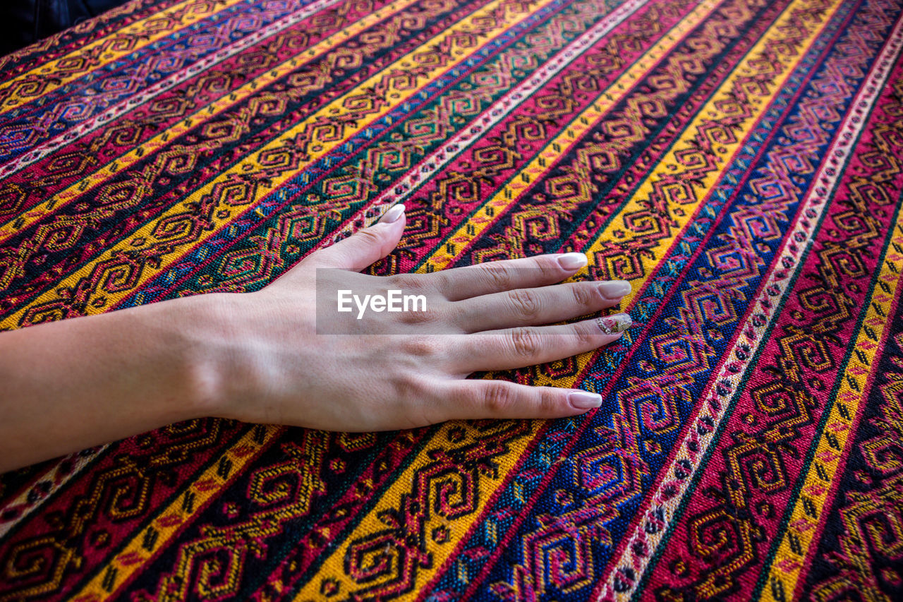 Cropped hand of woman touching patterned fabric