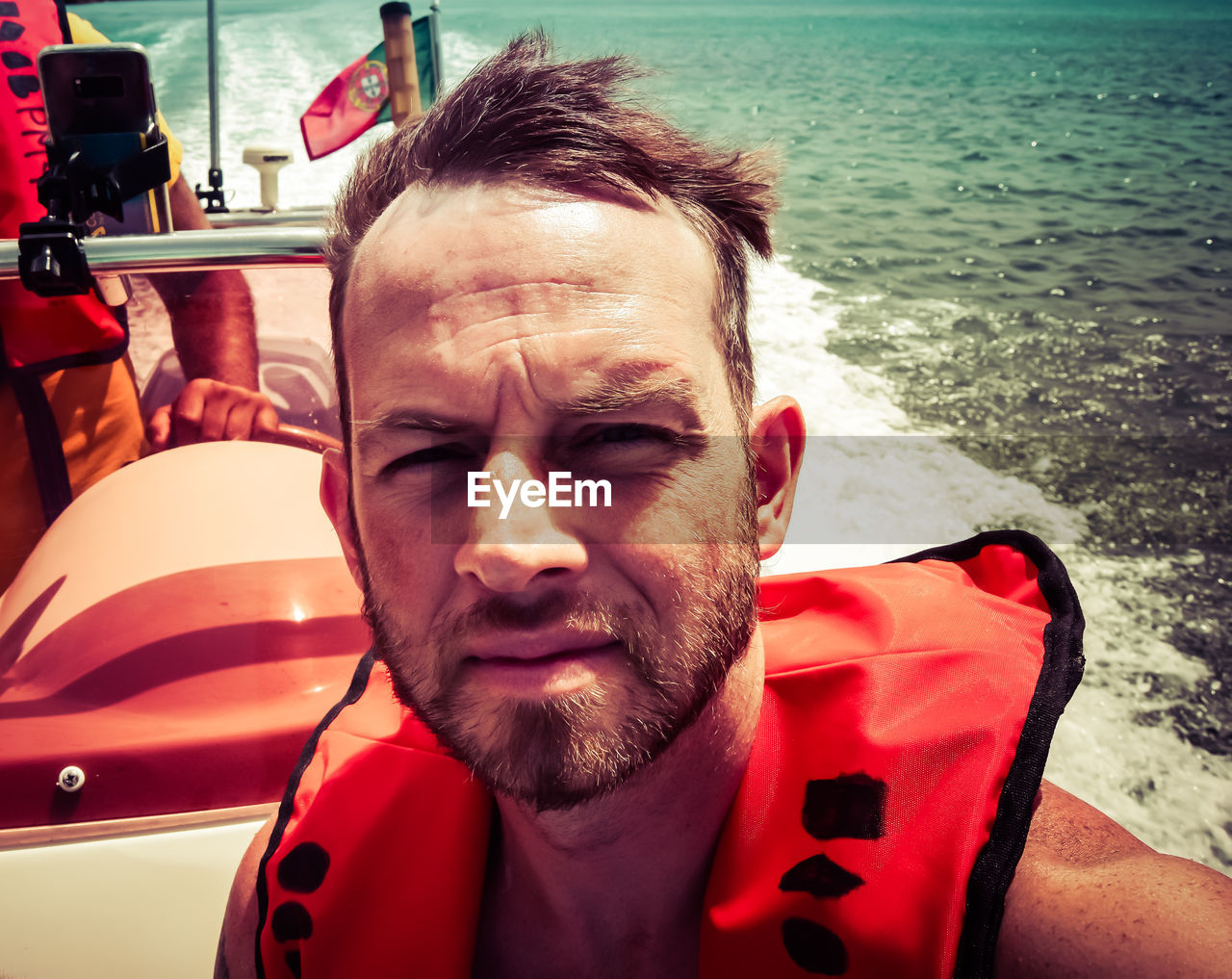 Portrait of shirtless man wearing life jacket while traveling in boat at sea