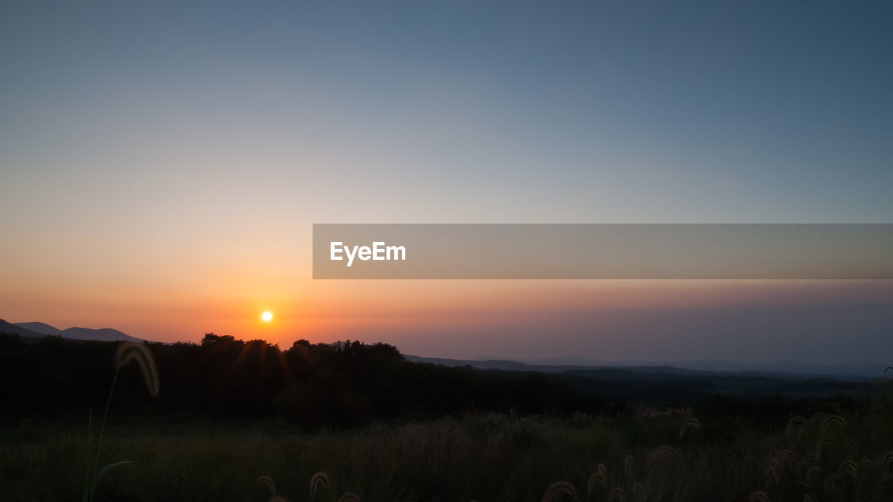 SCENIC VIEW OF AGRICULTURAL FIELD AGAINST SKY DURING SUNSET