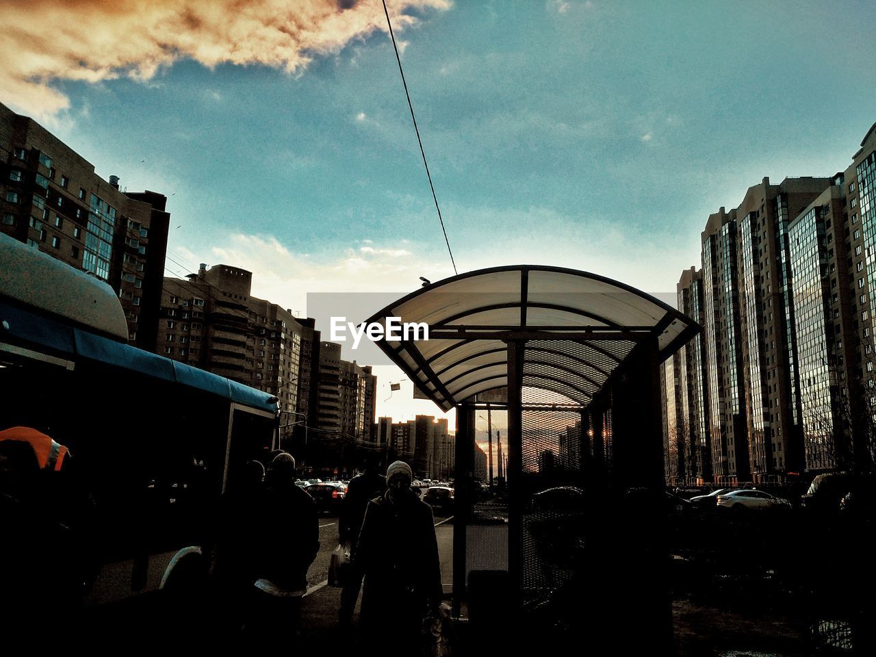 Silhouette people at bus stop in city during sunset