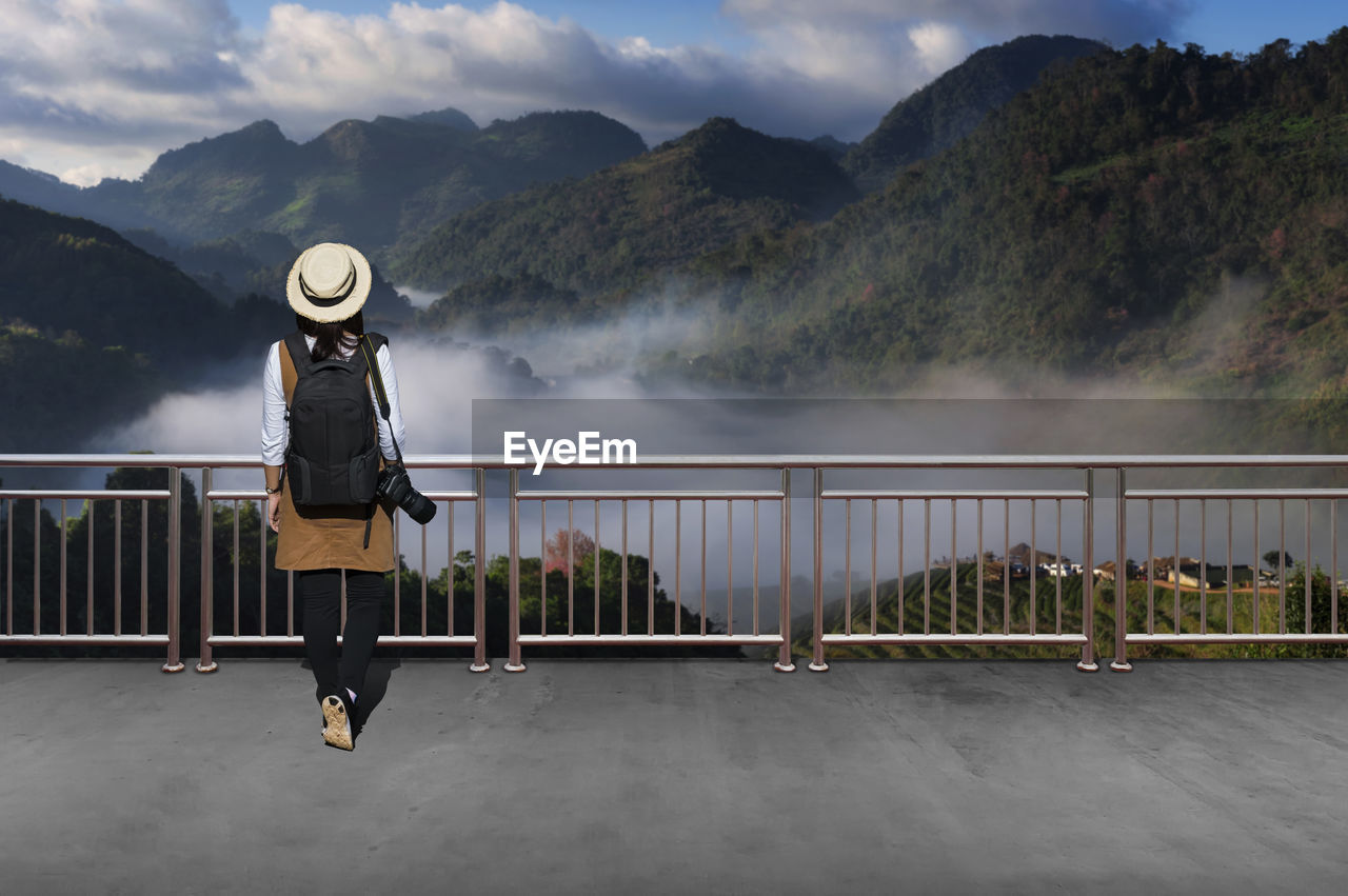 Woman standing by railing against mountain