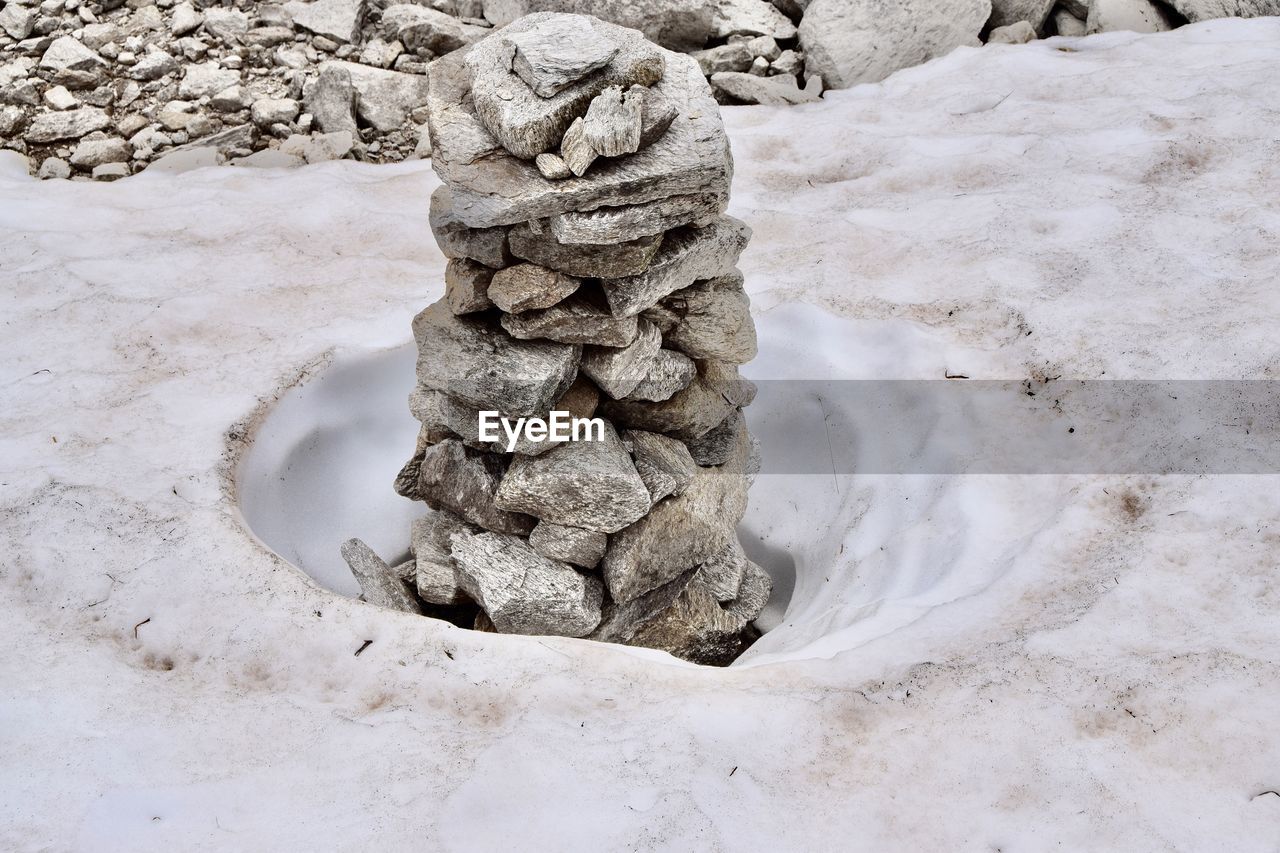 STACK OF STONES ON SNOW ON FIELD