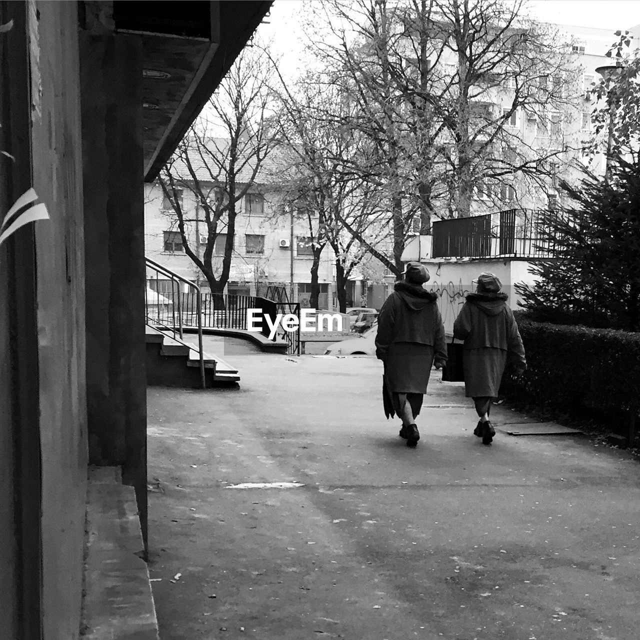 Rear view of friends walking footpath in city