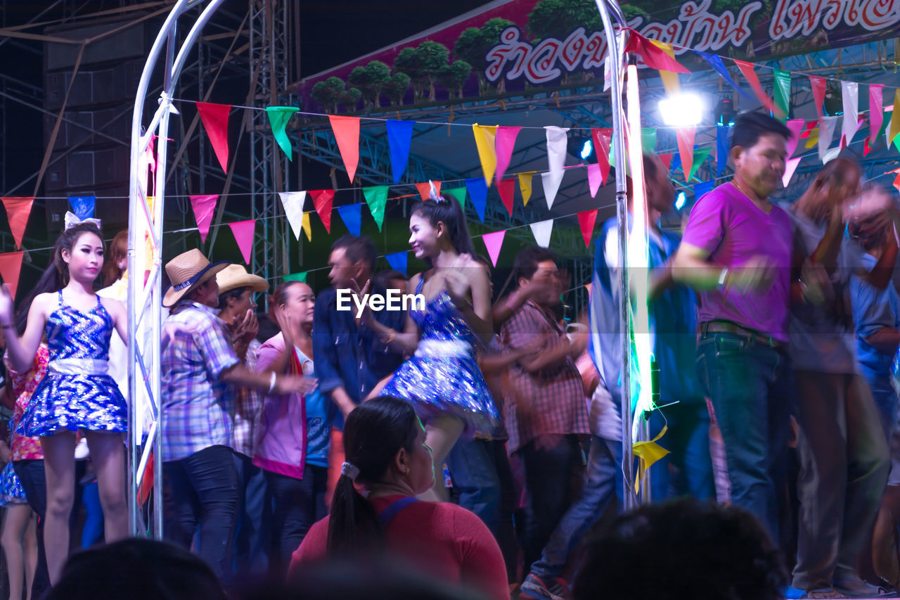 GROUP OF PEOPLE STANDING IN ILLUMINATED TRADITIONAL CLOTHING