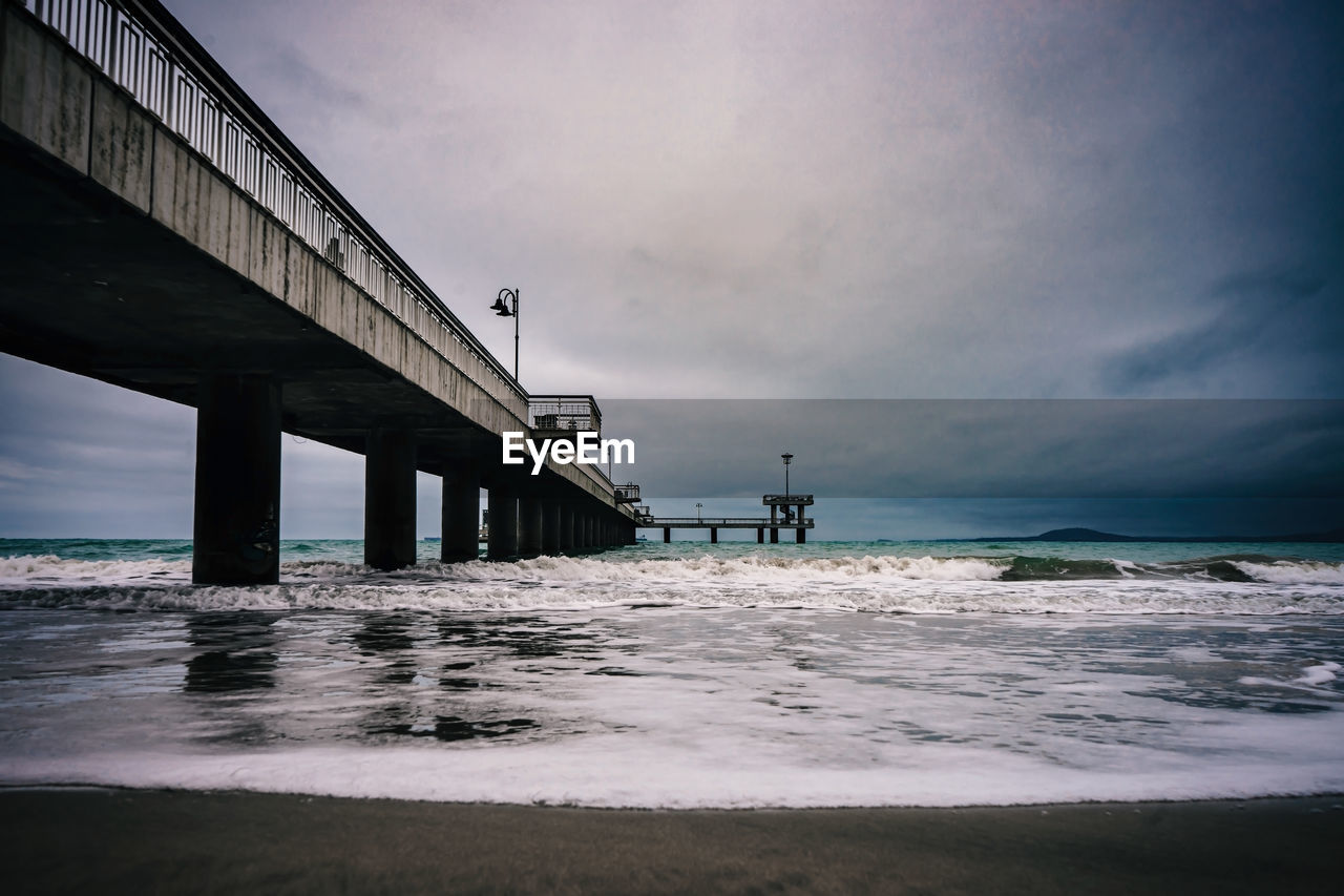 Bridge over sea against sky in a cloudy cold morning.