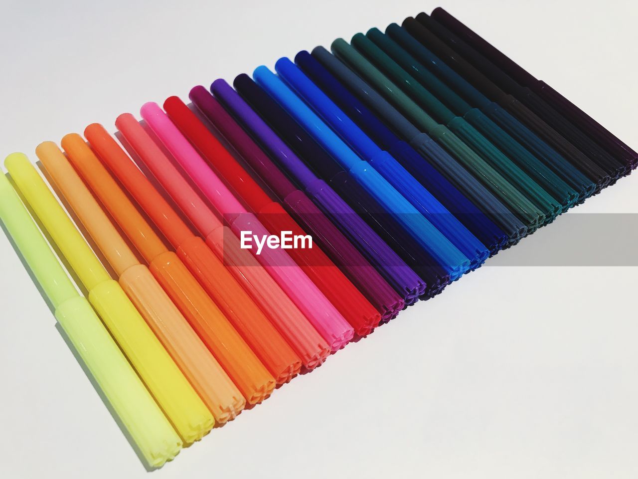 CLOSE-UP OF COLORED PENCILS OVER WHITE BACKGROUND