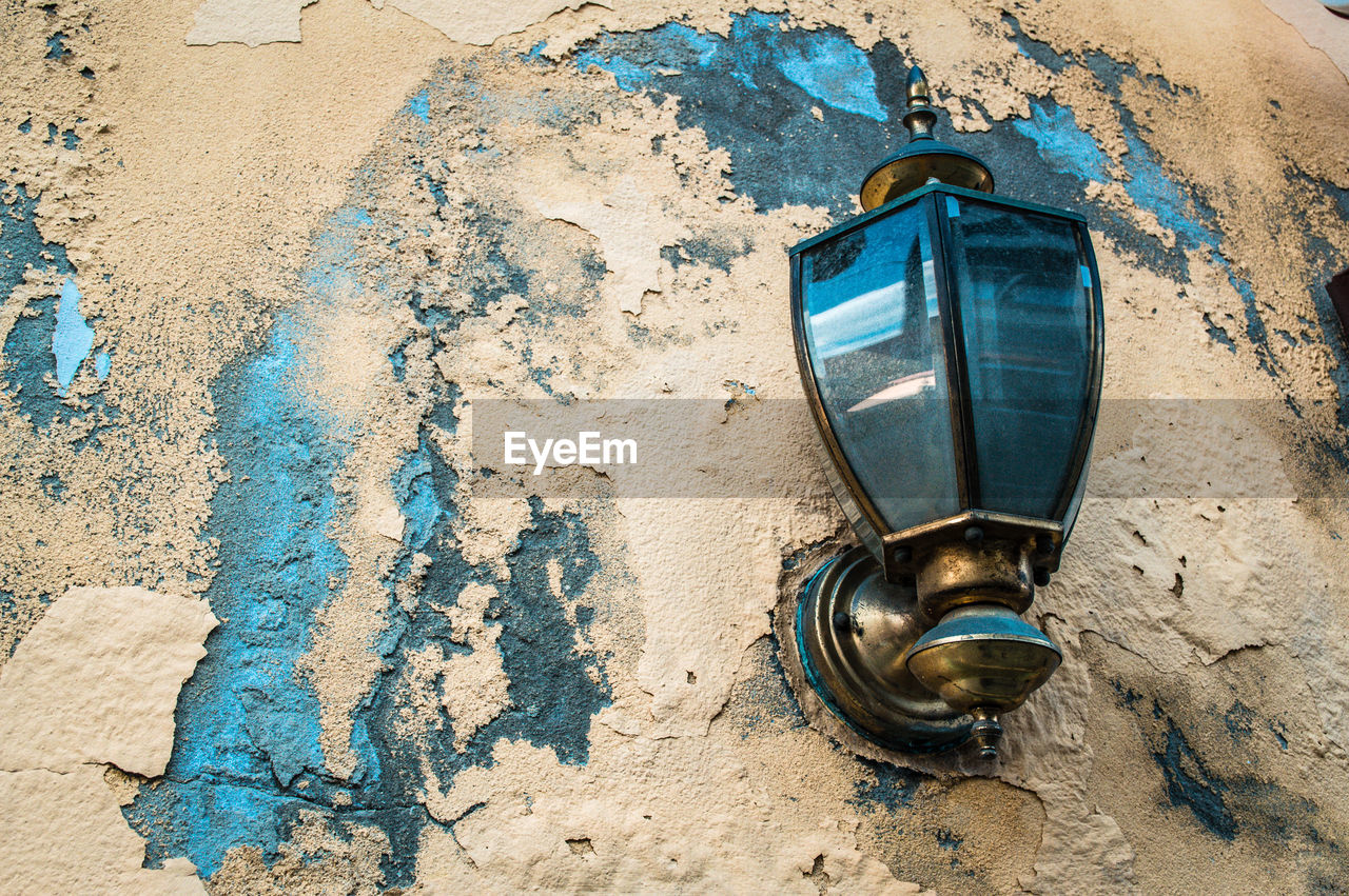 Close-up of old weathered wall with a vintage metal street lamp