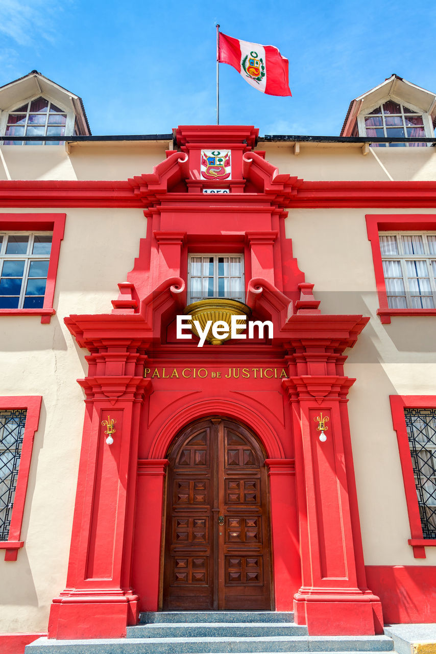 Low angle view of peruvian flag on courthouse against sky