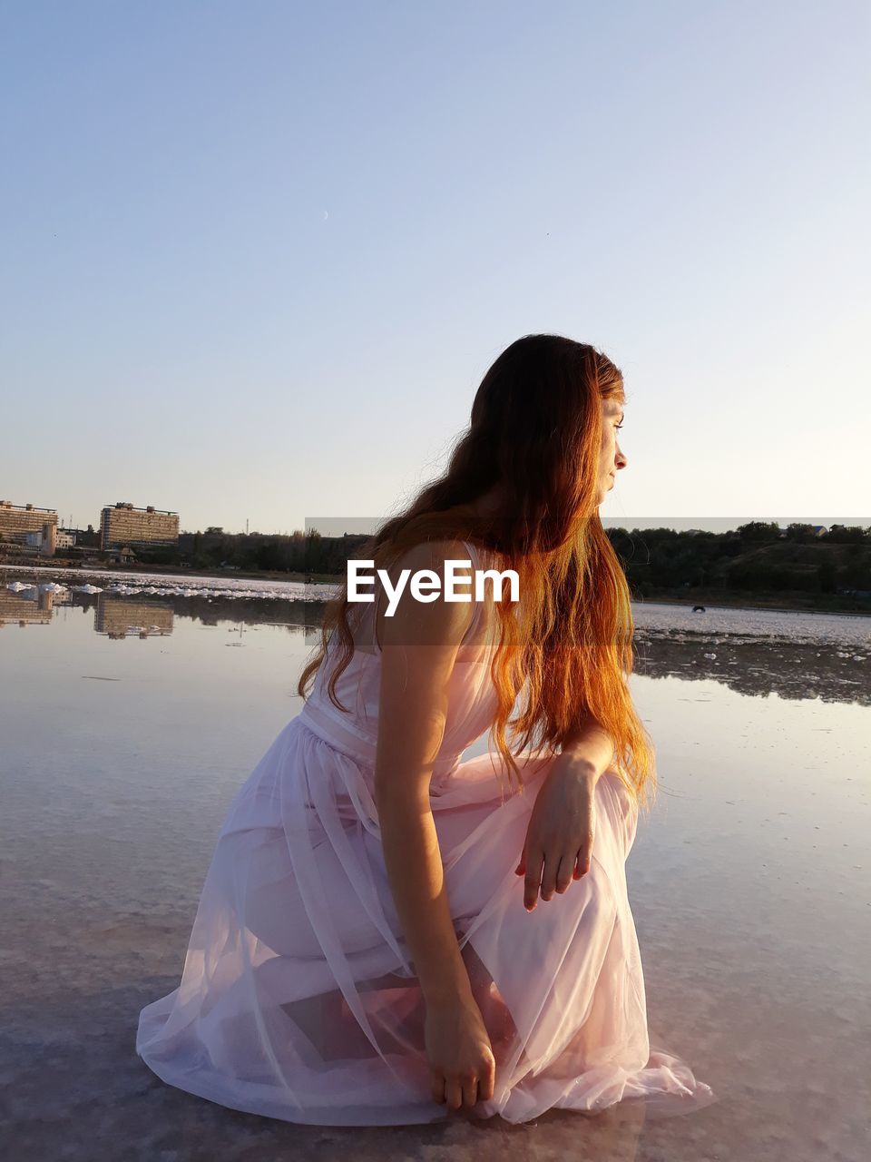 Woman at beach against clear sky during sunset