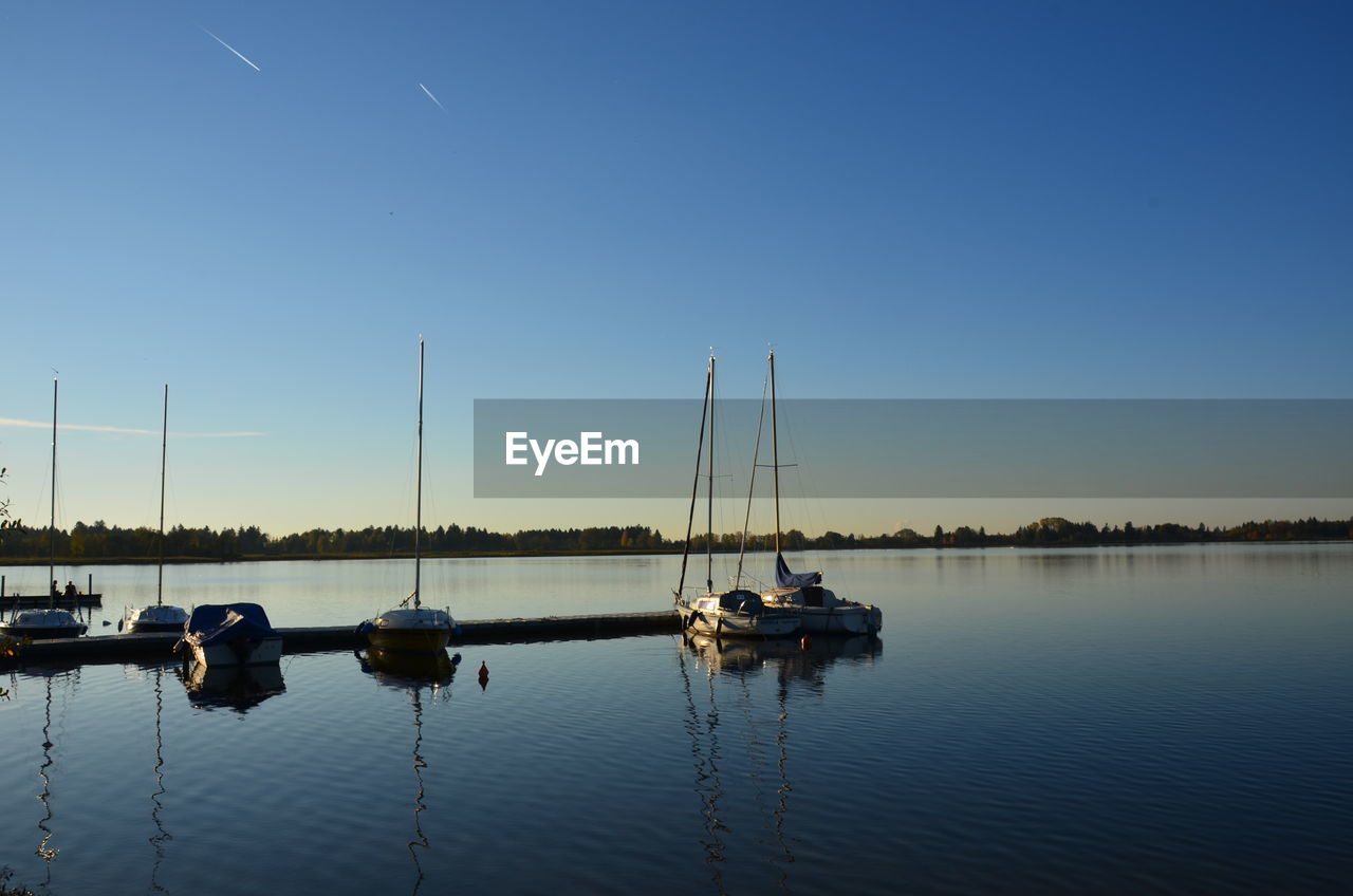 BOATS SAILING IN LAKE AGAINST CLEAR SKY