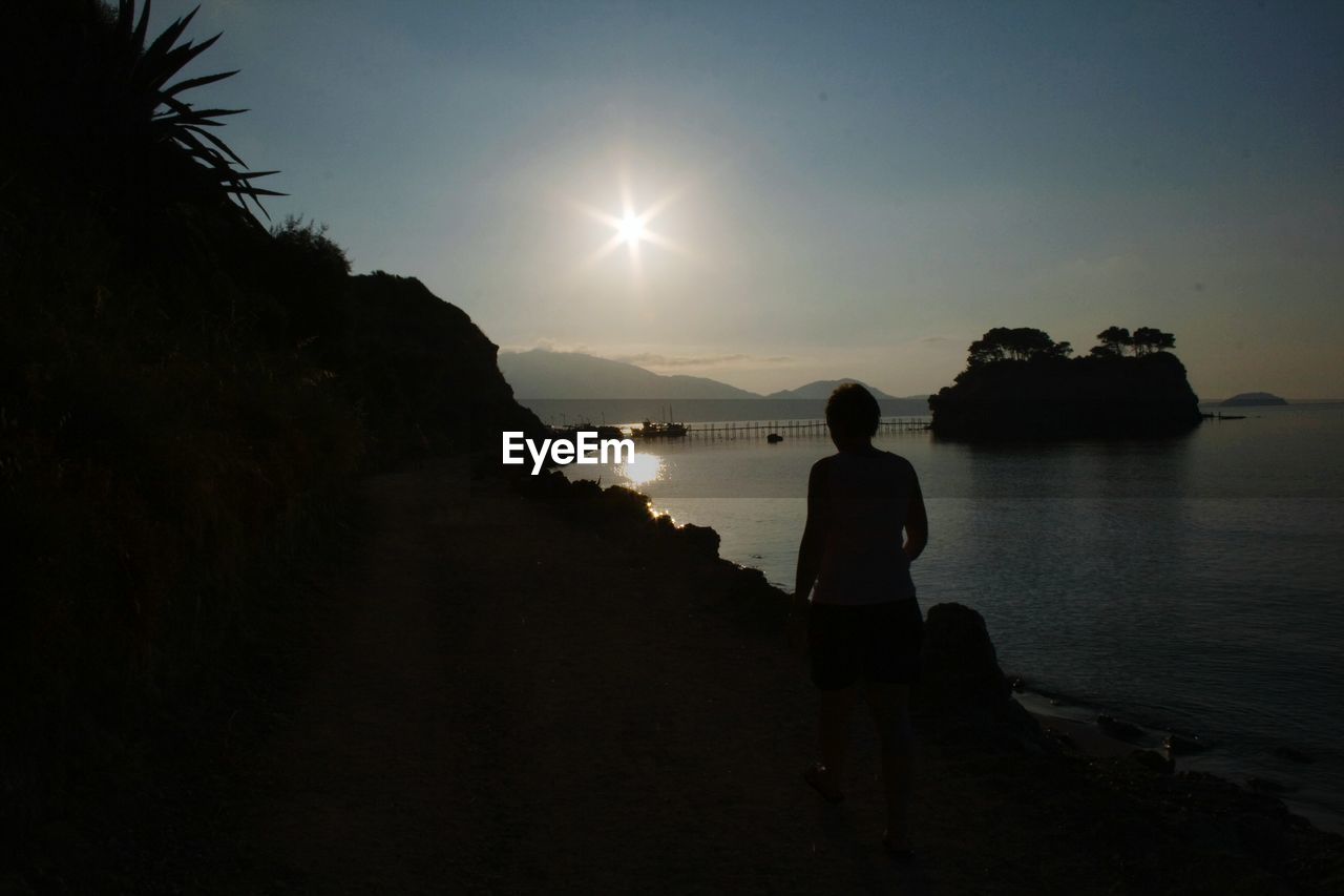 REAR VIEW OF TWO PEOPLE STANDING ON BEACH AT NIGHT