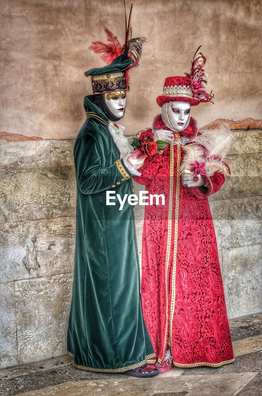 PORTRAIT OF WOMAN WITH RED MASK STANDING AGAINST WALL