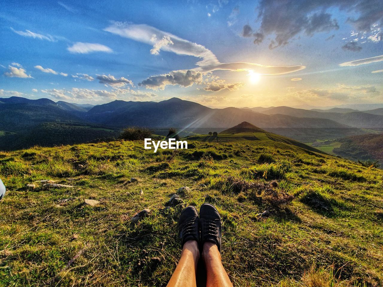 Person sitting on mountain against sky