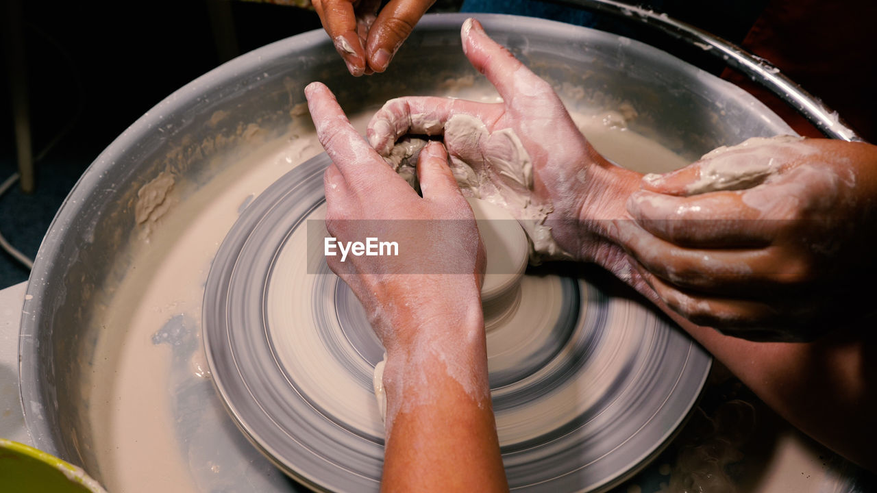A potter forms a beautiful creation out of white clay. lessons from a master in an open class