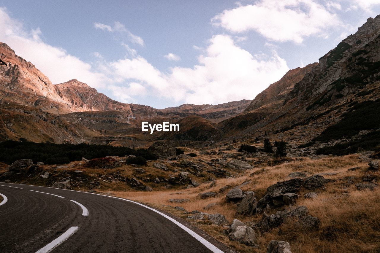 Road leading towards mountains against sky