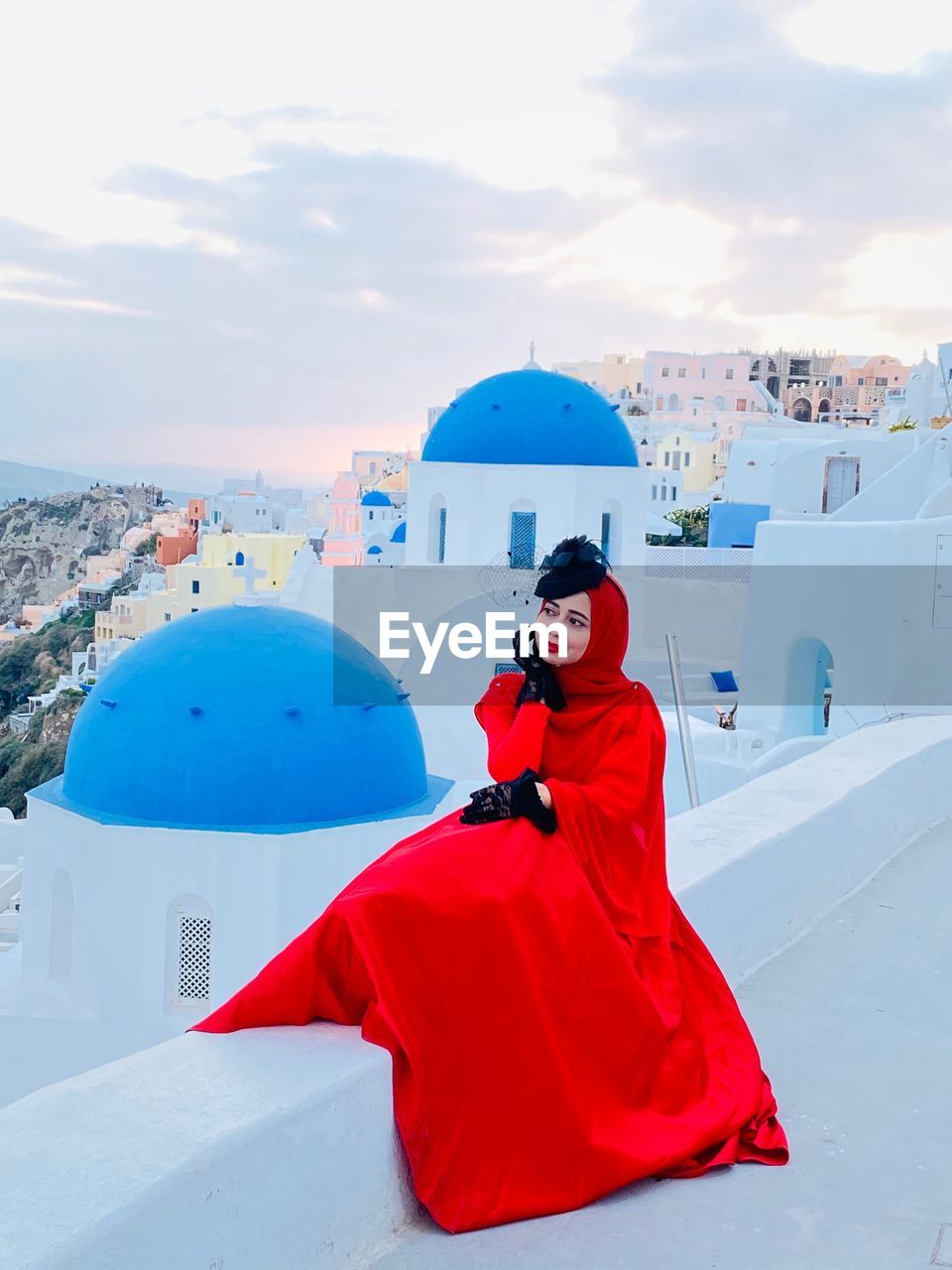 Woman on red dress sitting on the rooftop with the background of  blue sky and ocean