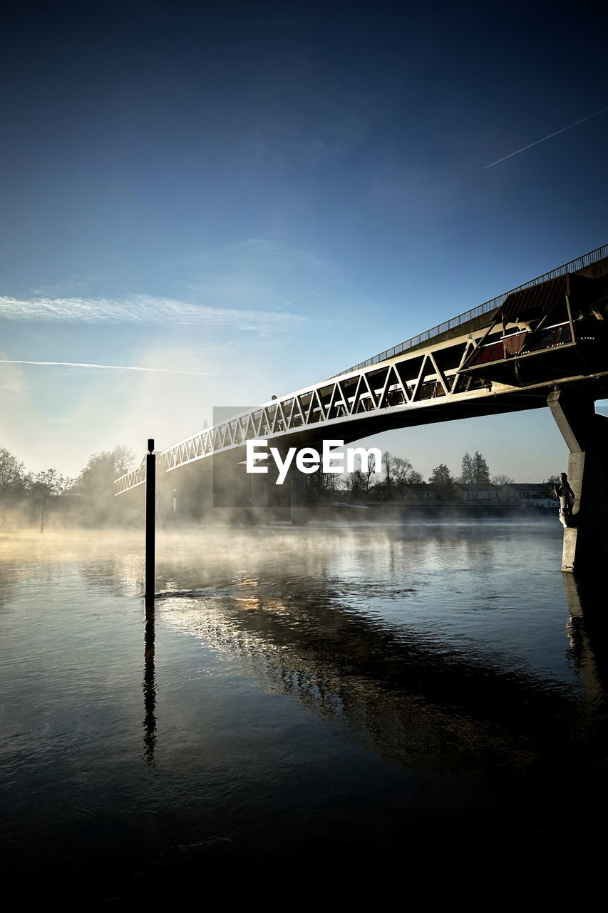bridge over river against sky at sunset