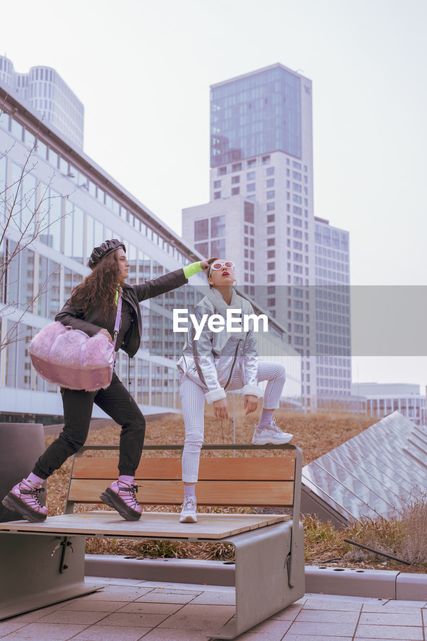 Woman touching friend hair bun against buildings in city