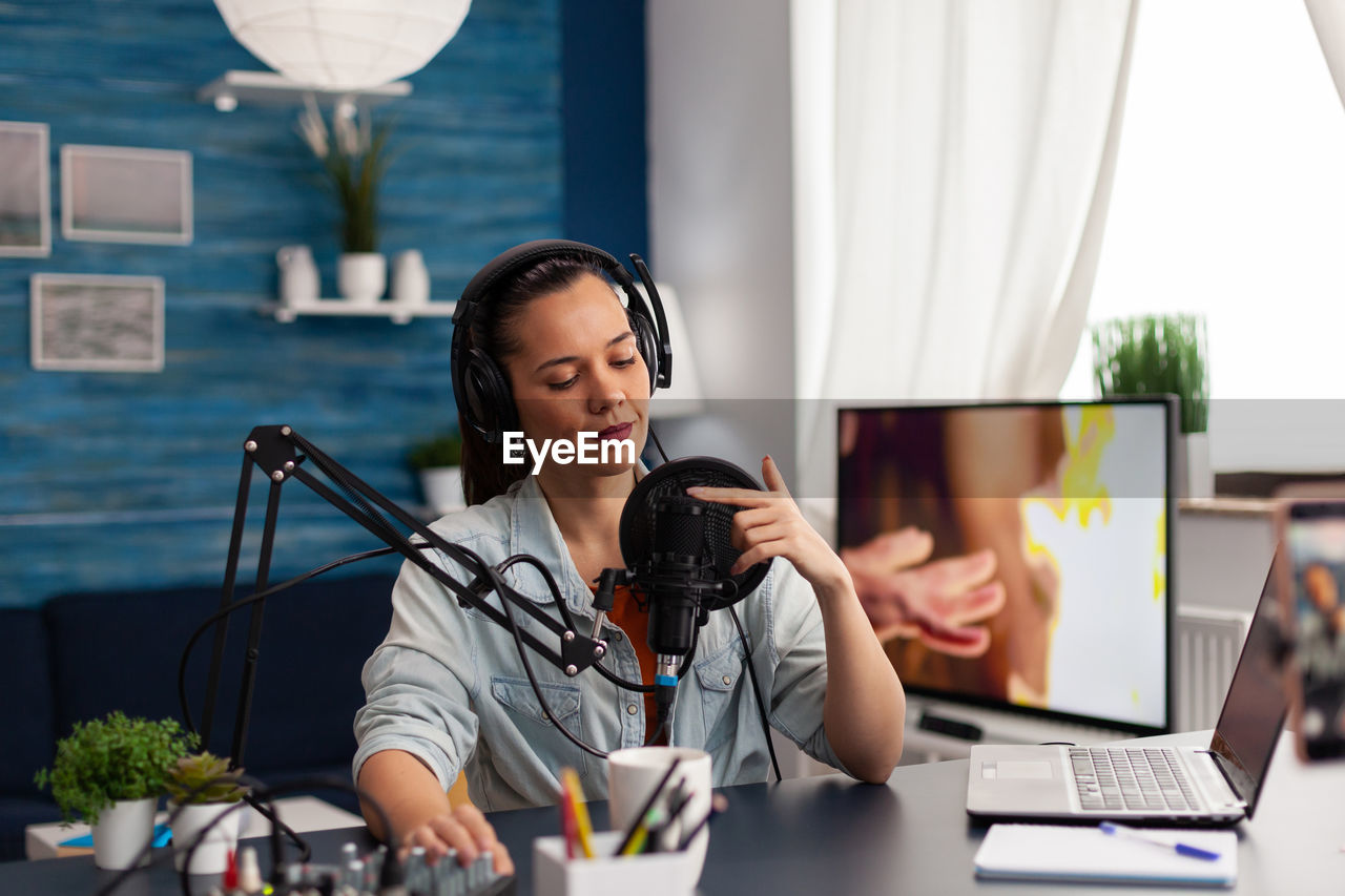 Woman wearing headphones doing podcast in office