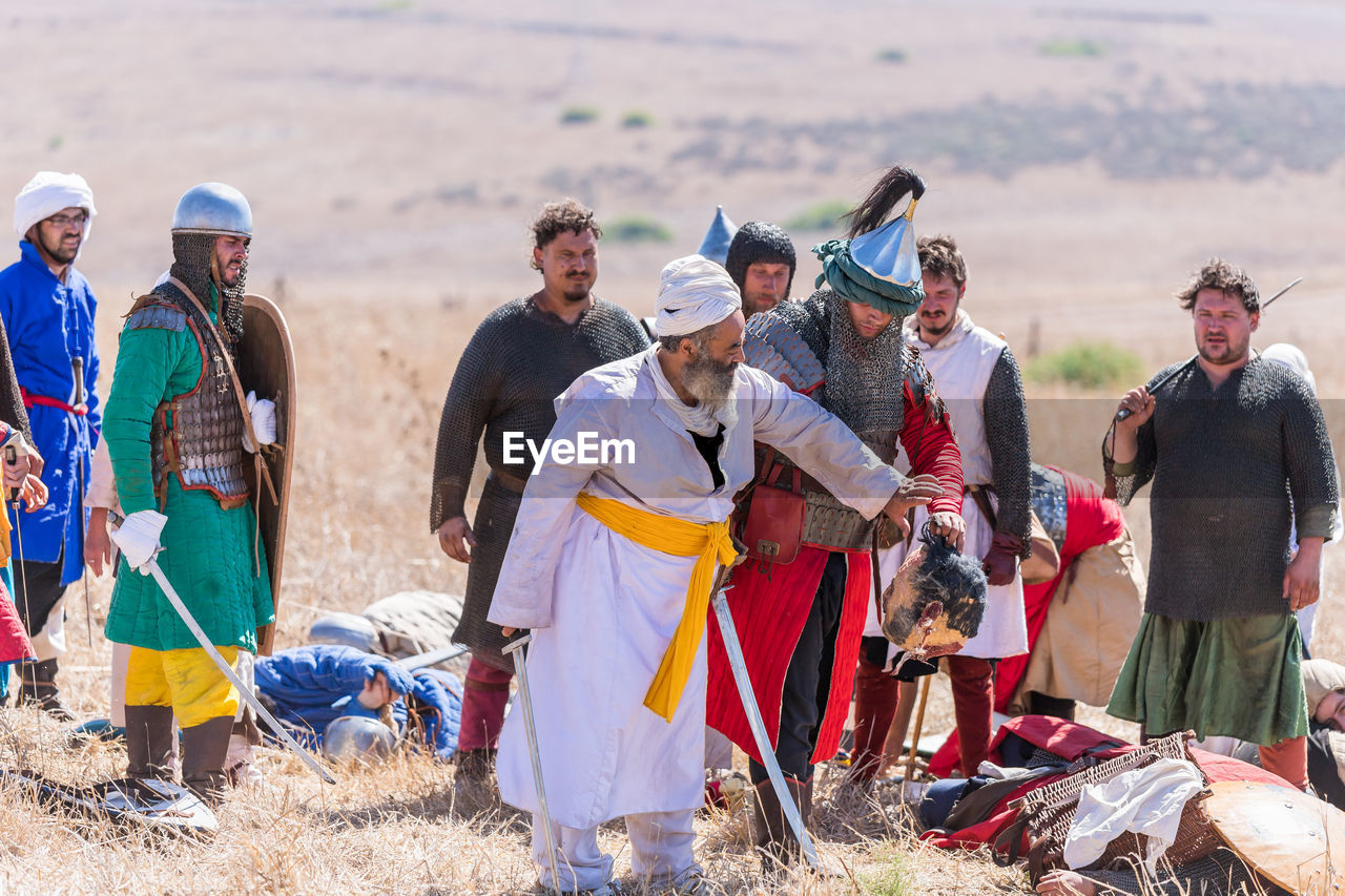 GROUP OF PEOPLE STANDING ON FIELD BY LAND