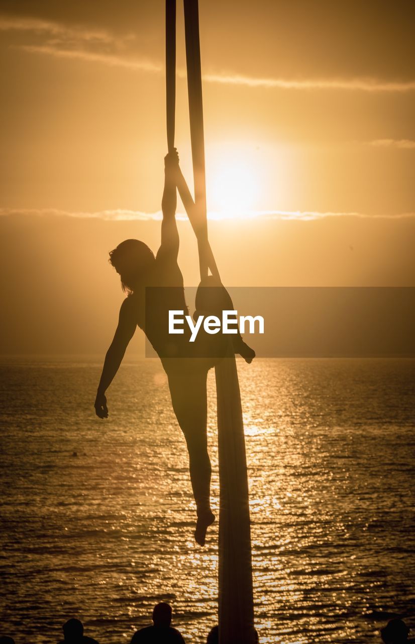 SILHOUETTE PEOPLE AT SEA SHORE AGAINST SKY DURING SUNSET