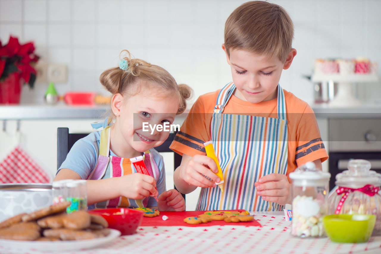 Portrait of cute girl and boy preparing food at kitchen