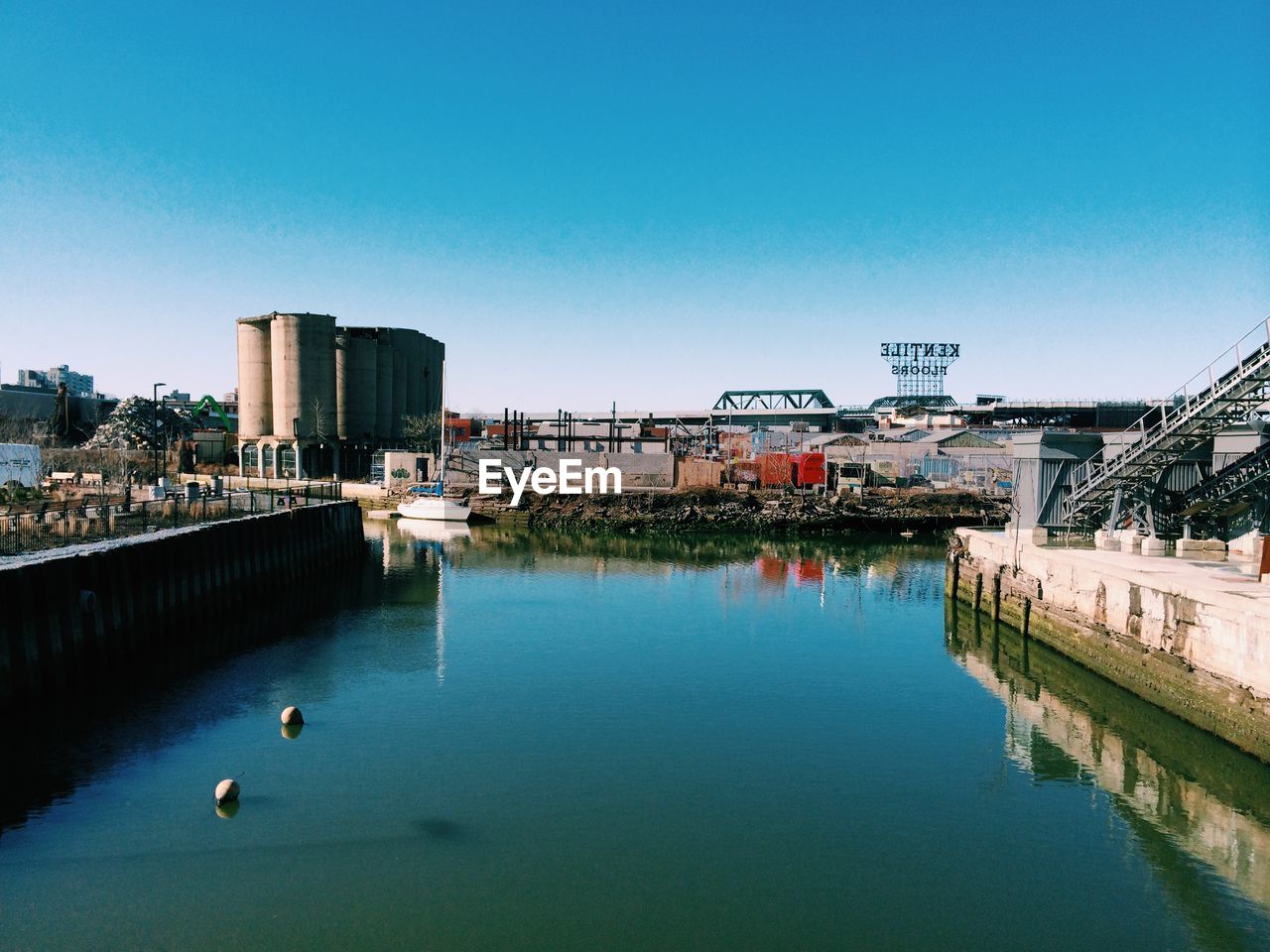 Gowns canal by industrial buildings against clear sky