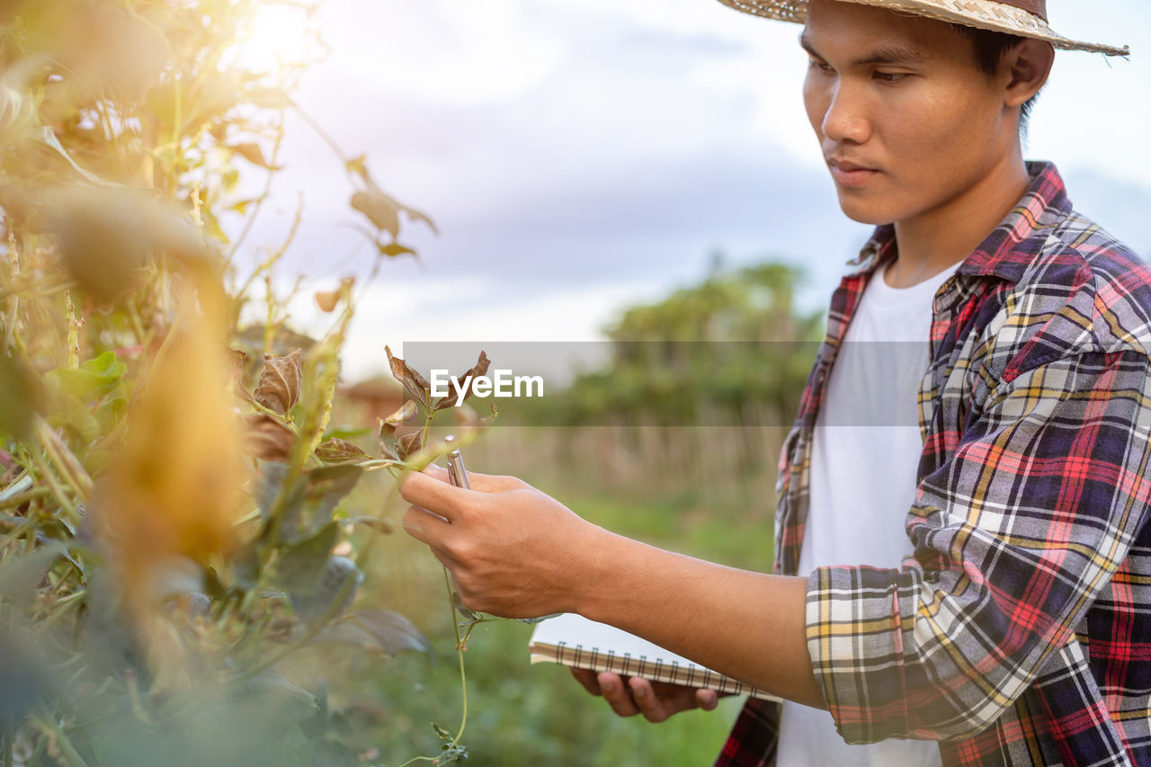 Young man looking at plant in farm