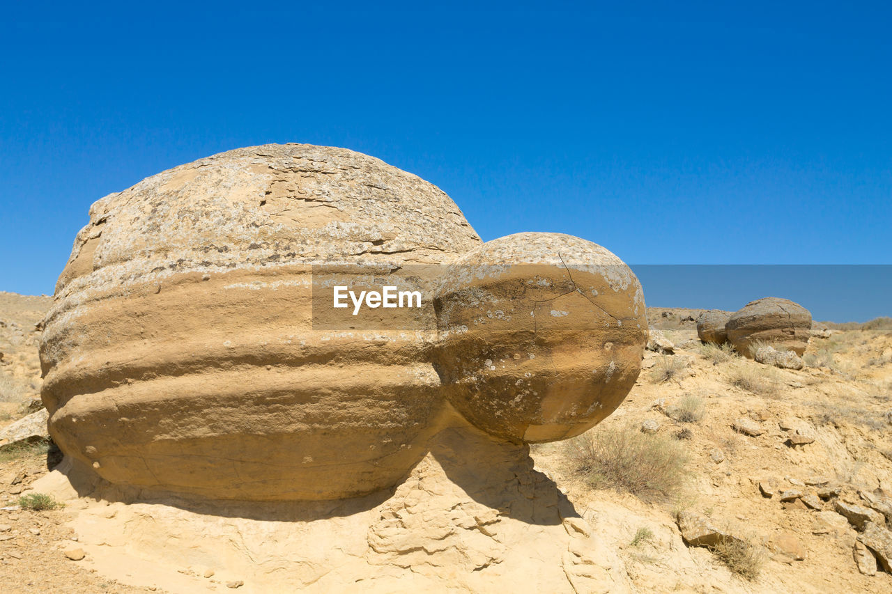 low angle view of rock formations in desert against clear blue sky