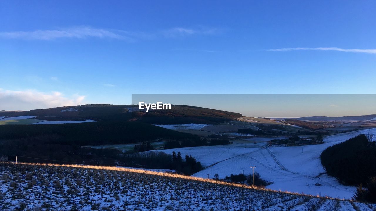 Scenic view of snowcapped mountains against blue sky