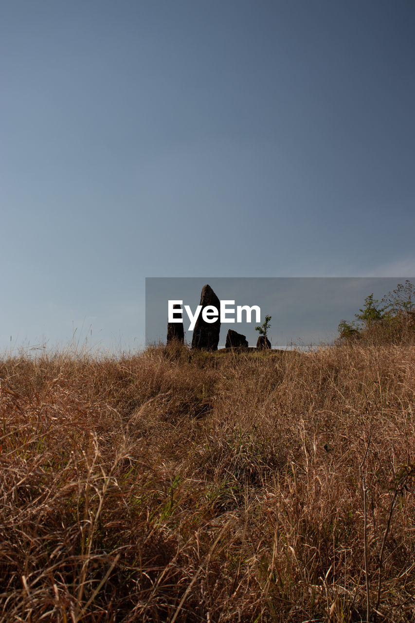 Standing sacred stone monoliths with bright blue sky and grass from a different perspective