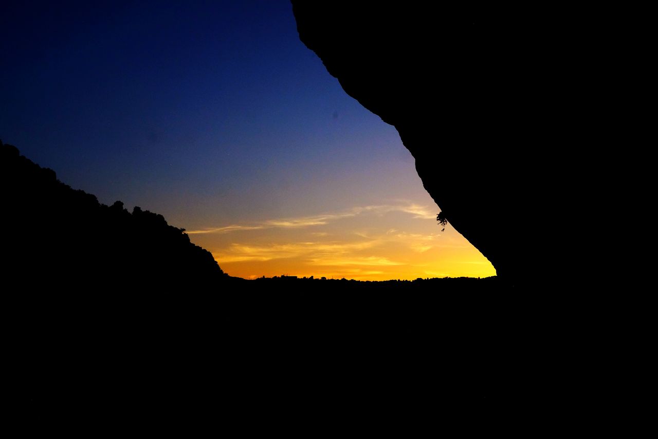 SILHOUETTE MOUNTAINS AGAINST ORANGE SKY