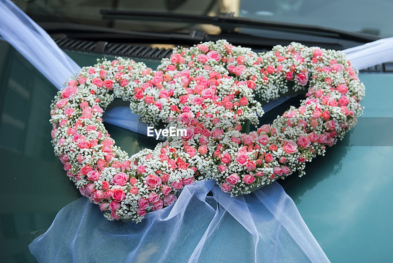 Heart shape decoration made from flowers on car hood during wedding