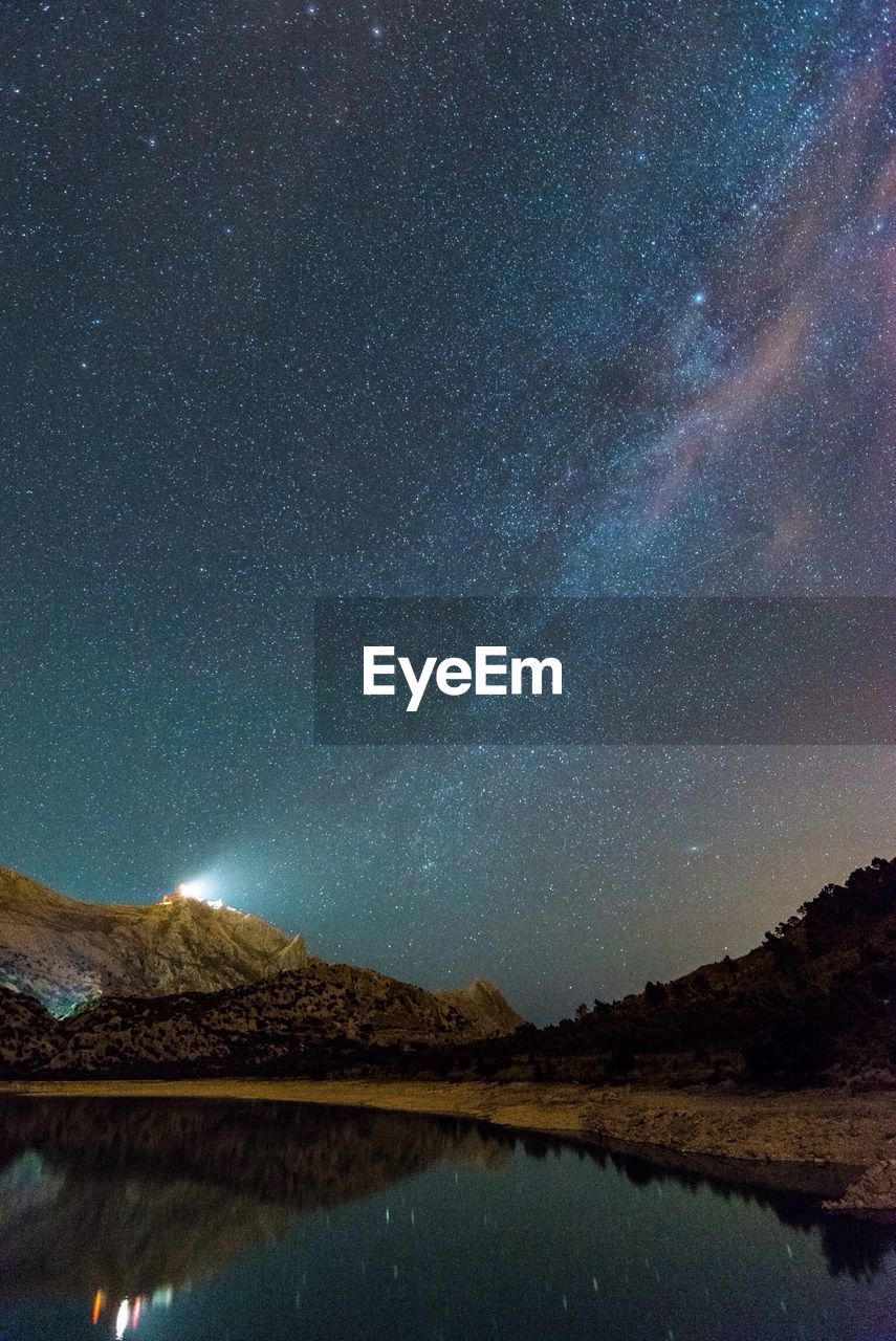 Scenic view of lake against mountains at night