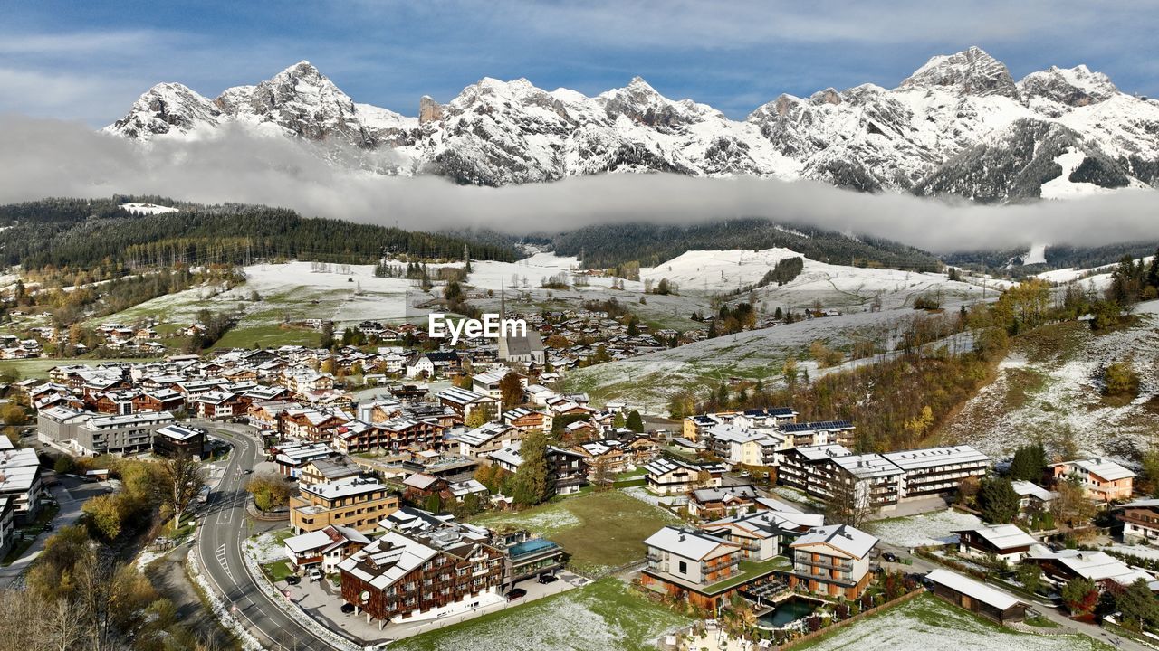 high angle view of townscape by snowcapped mountains against sky