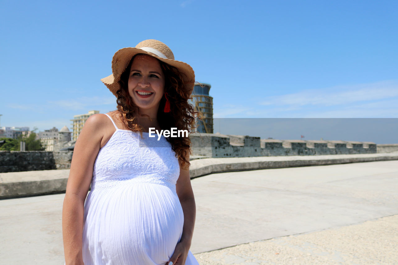 Portrait of smiling young woman standing against sky