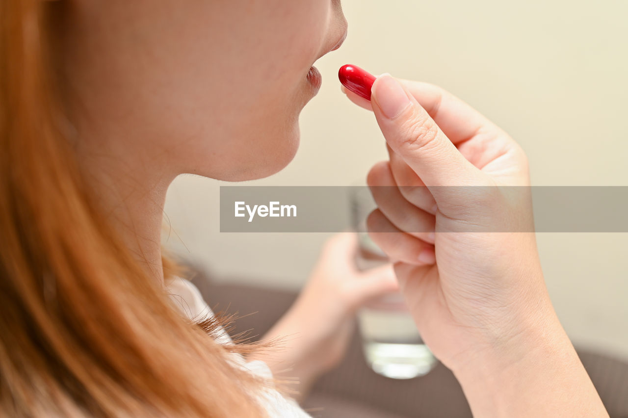 Cropped image of woman eating capsule