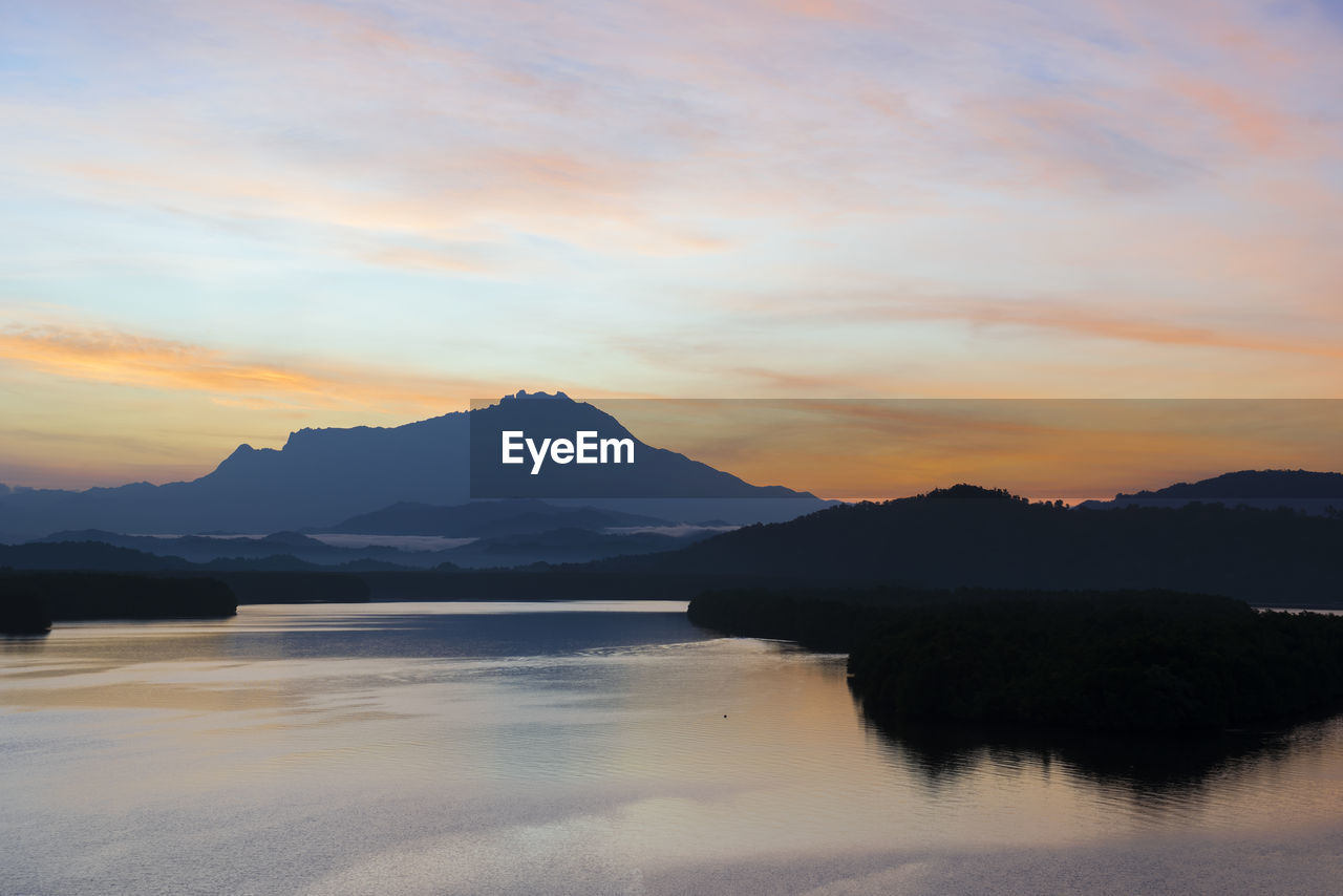 SCENIC VIEW OF LAKE AND SILHOUETTE MOUNTAINS AGAINST SKY DURING SUNSET