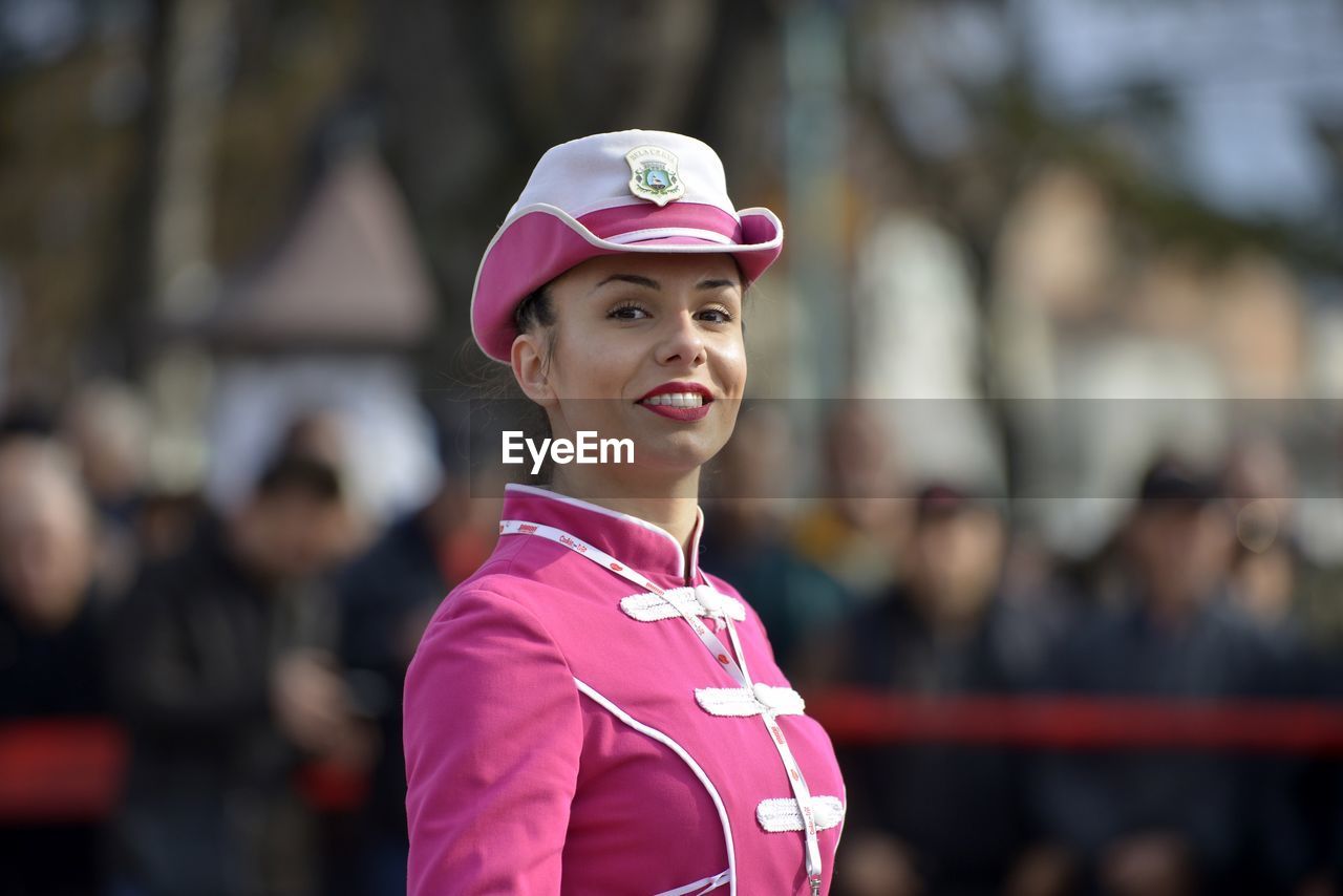 CLOSE-UP OF SMILING WOMAN STANDING ON PINK OUTDOORS