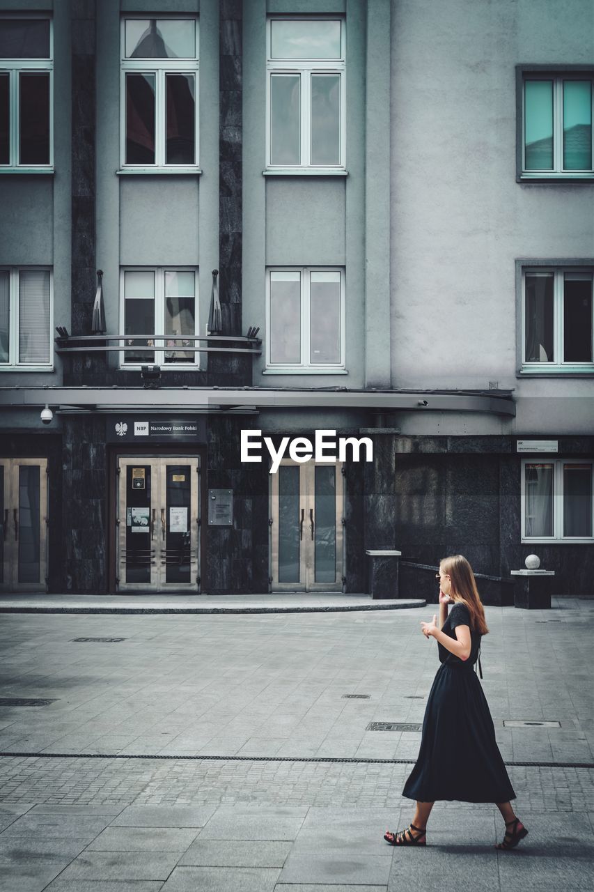 Full length of woman sitting outside building