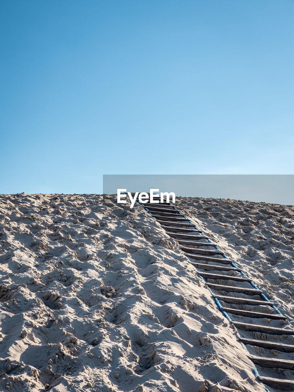 Scenic view of sand covered landscape against clear blue sky