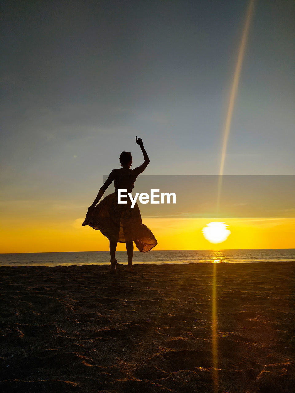 Silhouette people on beach against sky during sunset