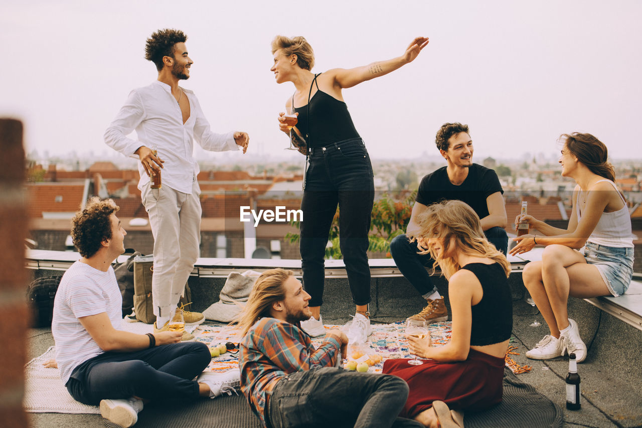 Happy people dancing while enjoying music with friends on terrace at rooftop party