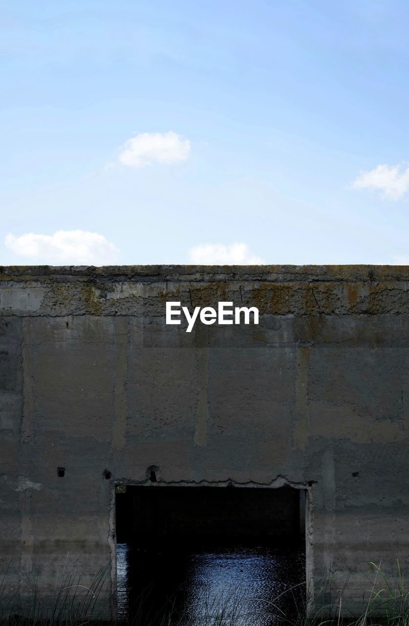 LOW ANGLE VIEW OF WALL ON BUILDING AGAINST SKY