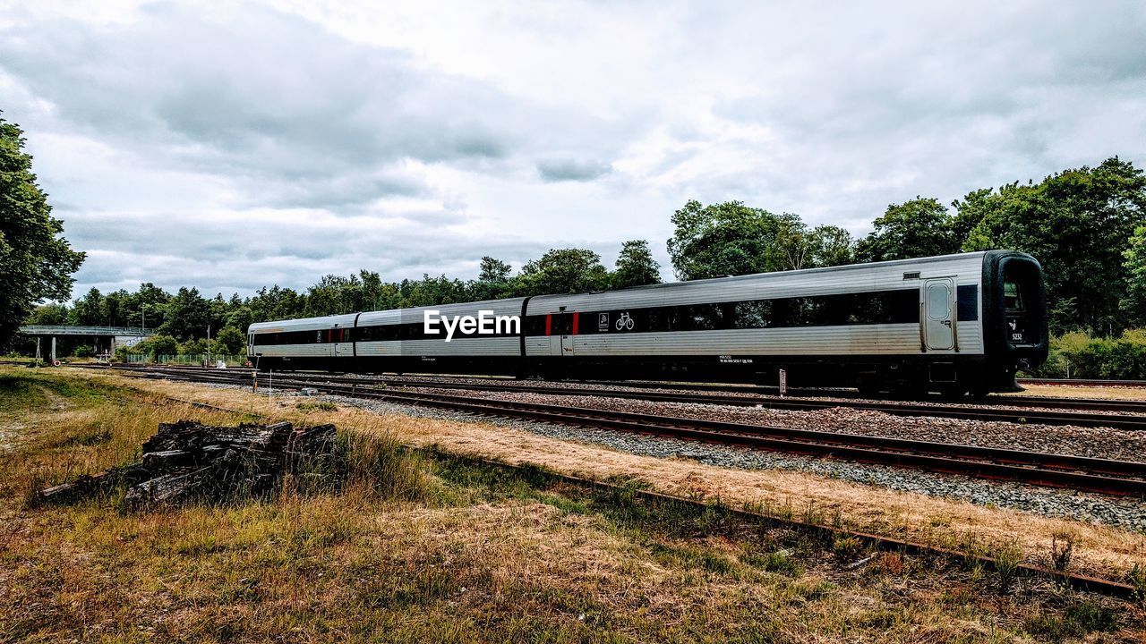 TRAIN BY RAILROAD TRACK AGAINST SKY