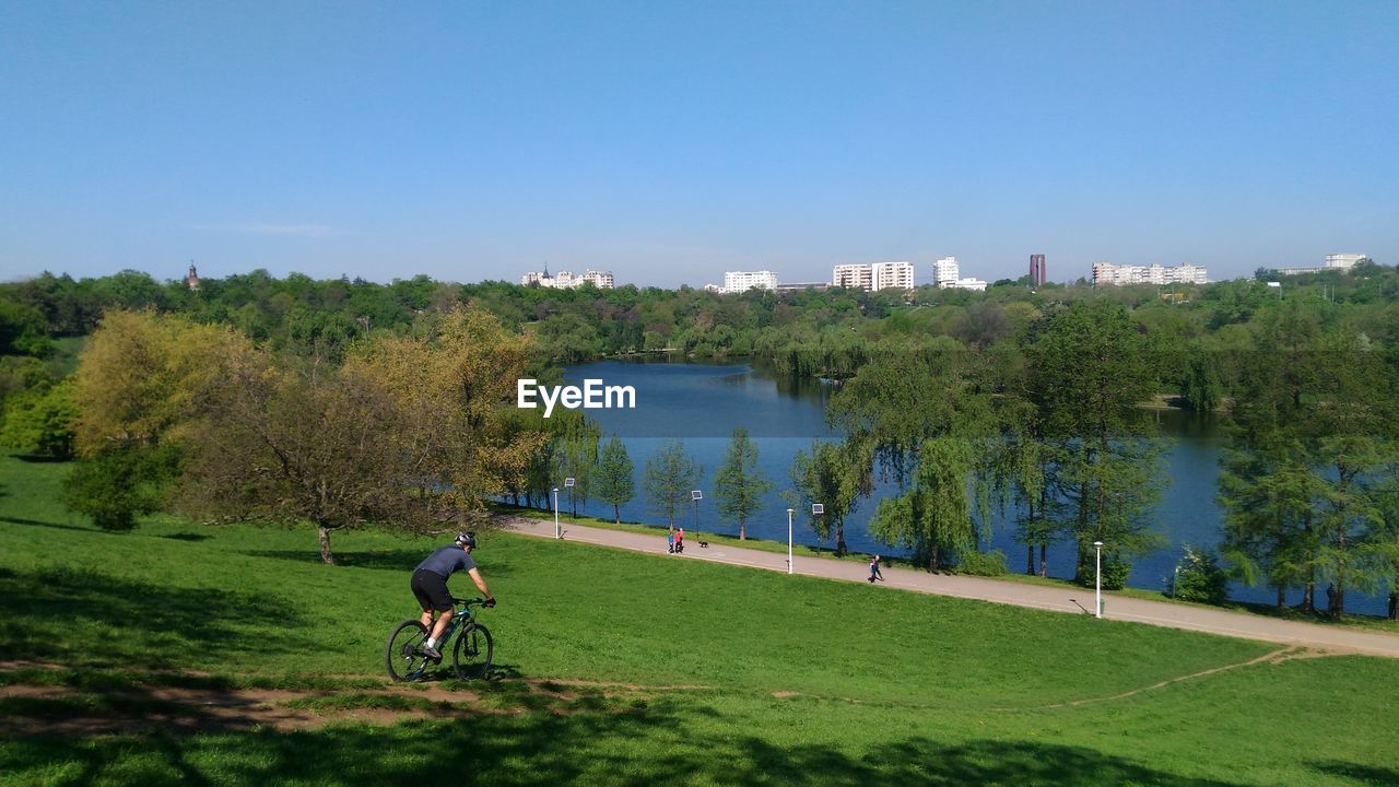 Man cycling on field against clear sky