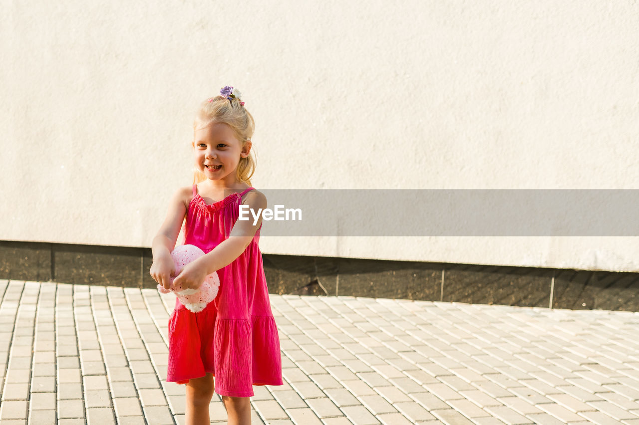 portrait of smiling young woman standing against wall