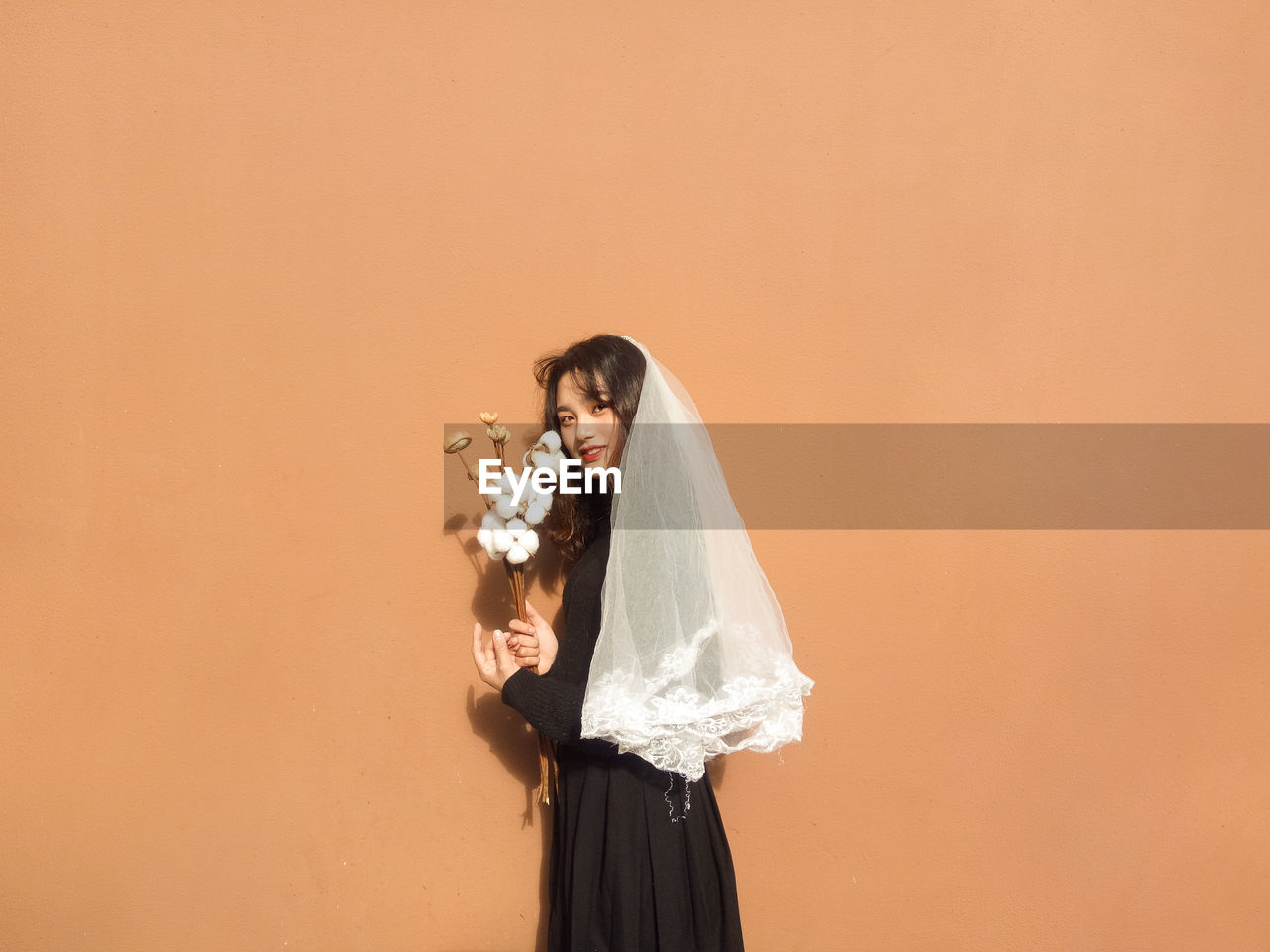 Portrait of bride standing against orange background