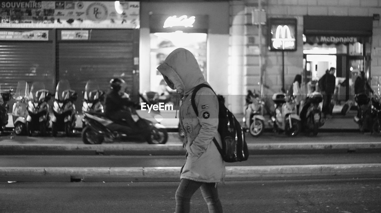 Side view of woman walking on road in city at night